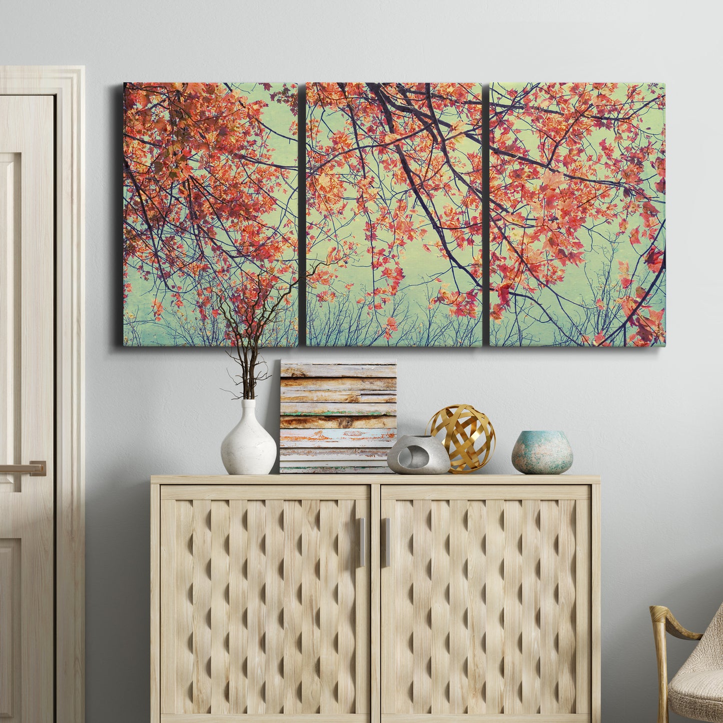 Three-panel canvas wall art featuring autumn foliage landscape photograph, displayed above a cabinet in an entryway.