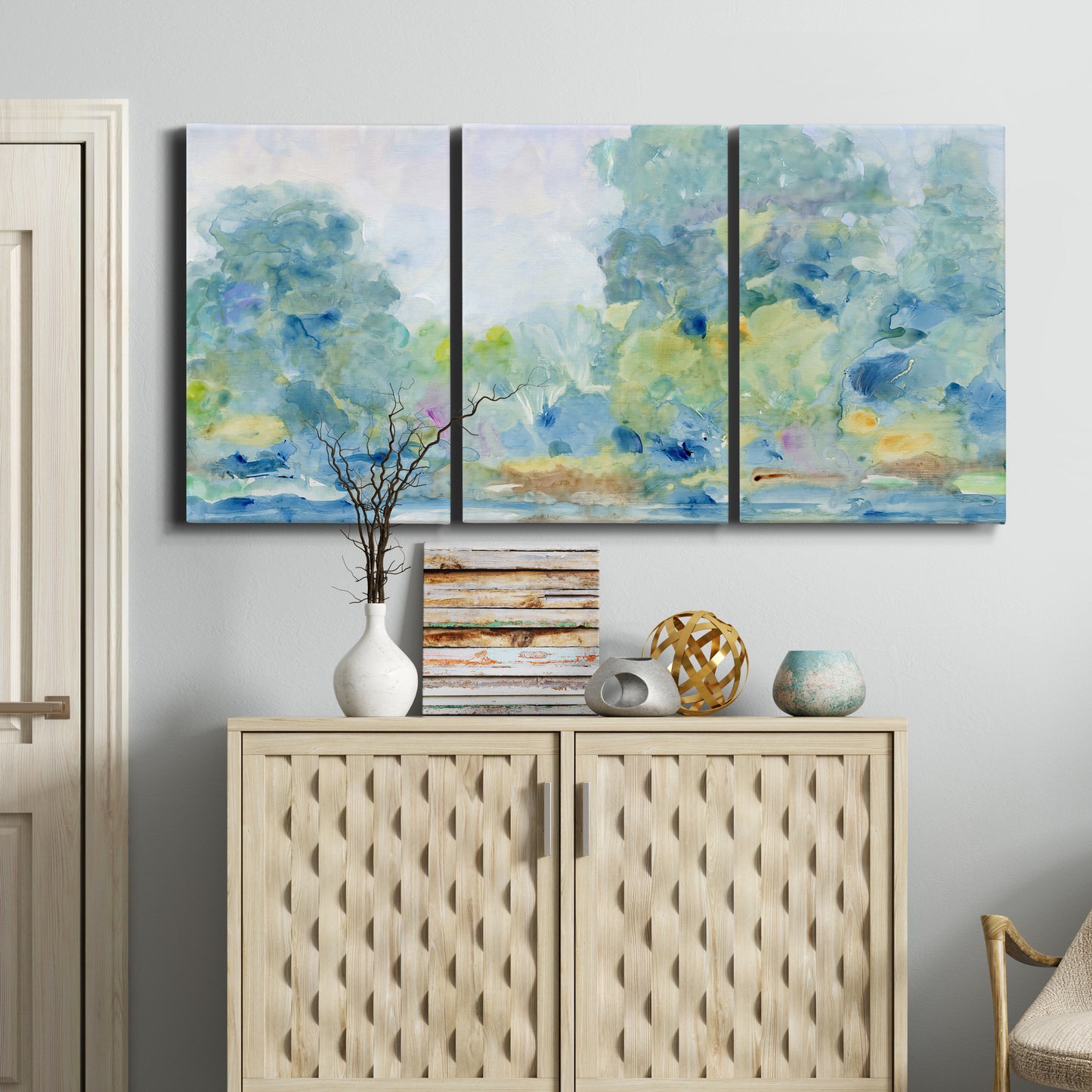 Three-panel canvas wall art featuring quiet abstract morning landscape, displayed above a cabinet in an entryway.