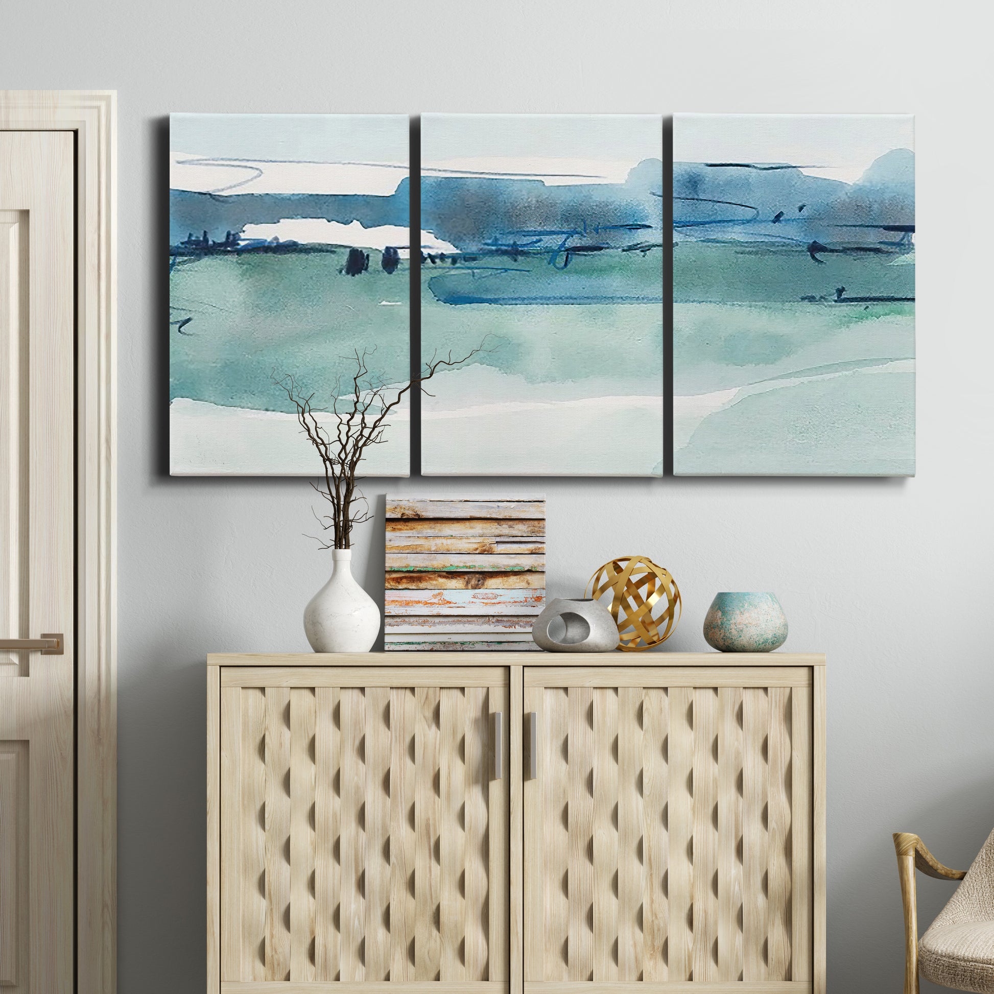 Three-panel canvas wall art featuring minimalist ultramarine abstract vista, displayed above a cabinet in an entryway.