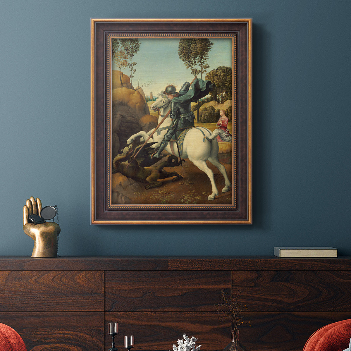 Religious painting of Saint George slaying the dragon by Raphael in an ornate bronzed mahogany wood frame displayed in a dark-toned interior setting.