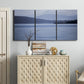 Three-panel canvas wall art featuring calm blue water landscape, displayed above a cabinet in an entryway.