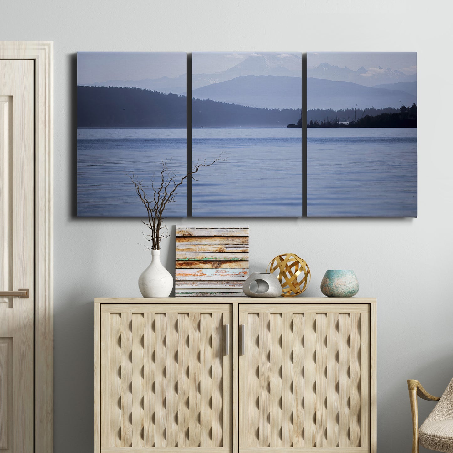 Three-panel canvas wall art featuring calm blue water landscape, displayed above a cabinet in an entryway.