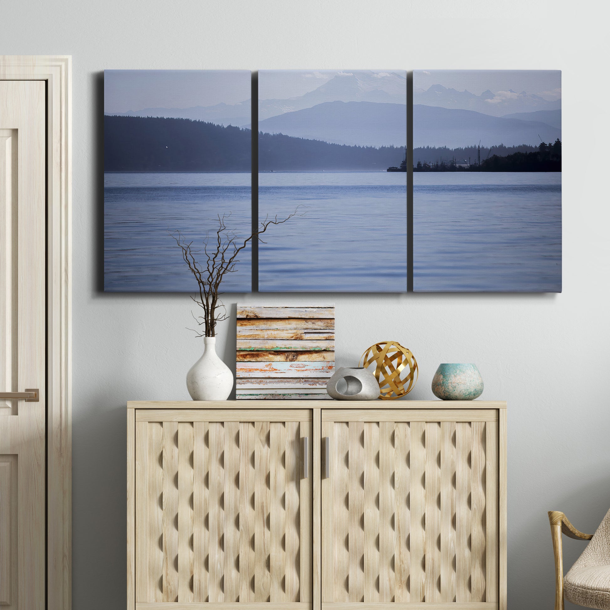Three-panel canvas wall art featuring calm blue water landscape, displayed above a cabinet in an entryway.