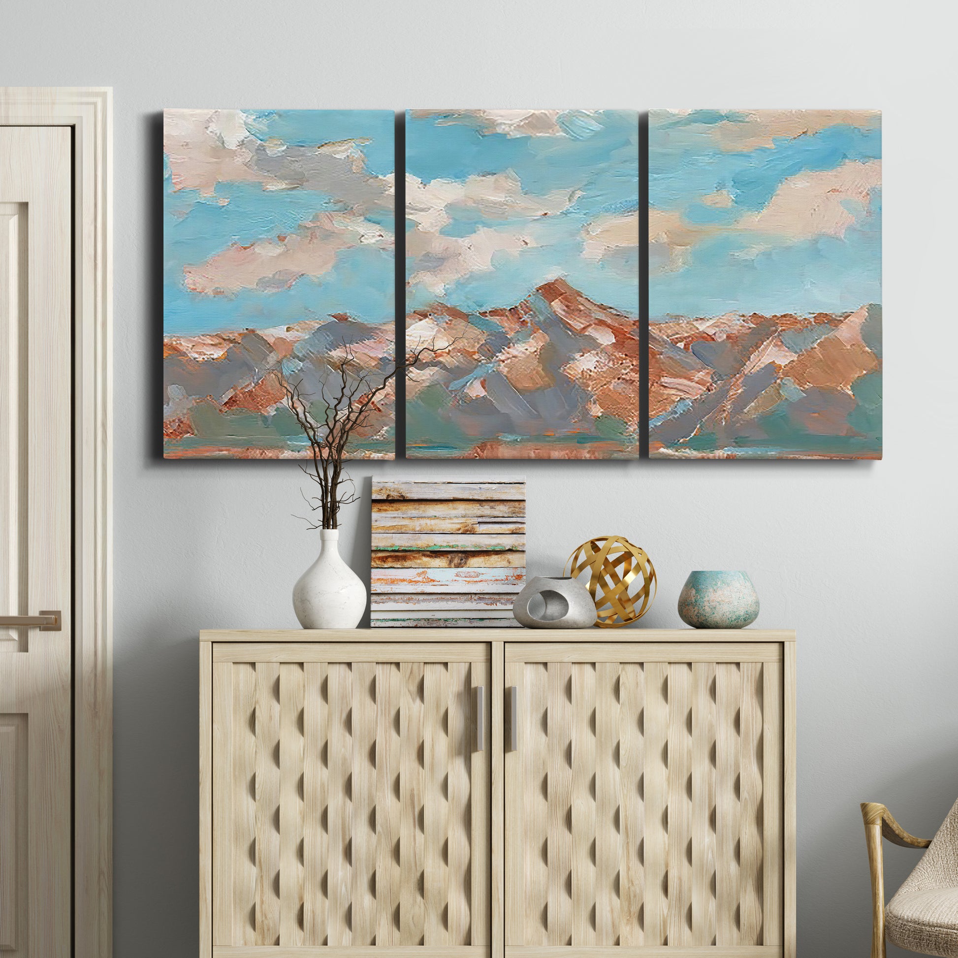 Three-panel canvas wall art featuring soft pastel western hills landscape, displayed above a cabinet in an entryway.