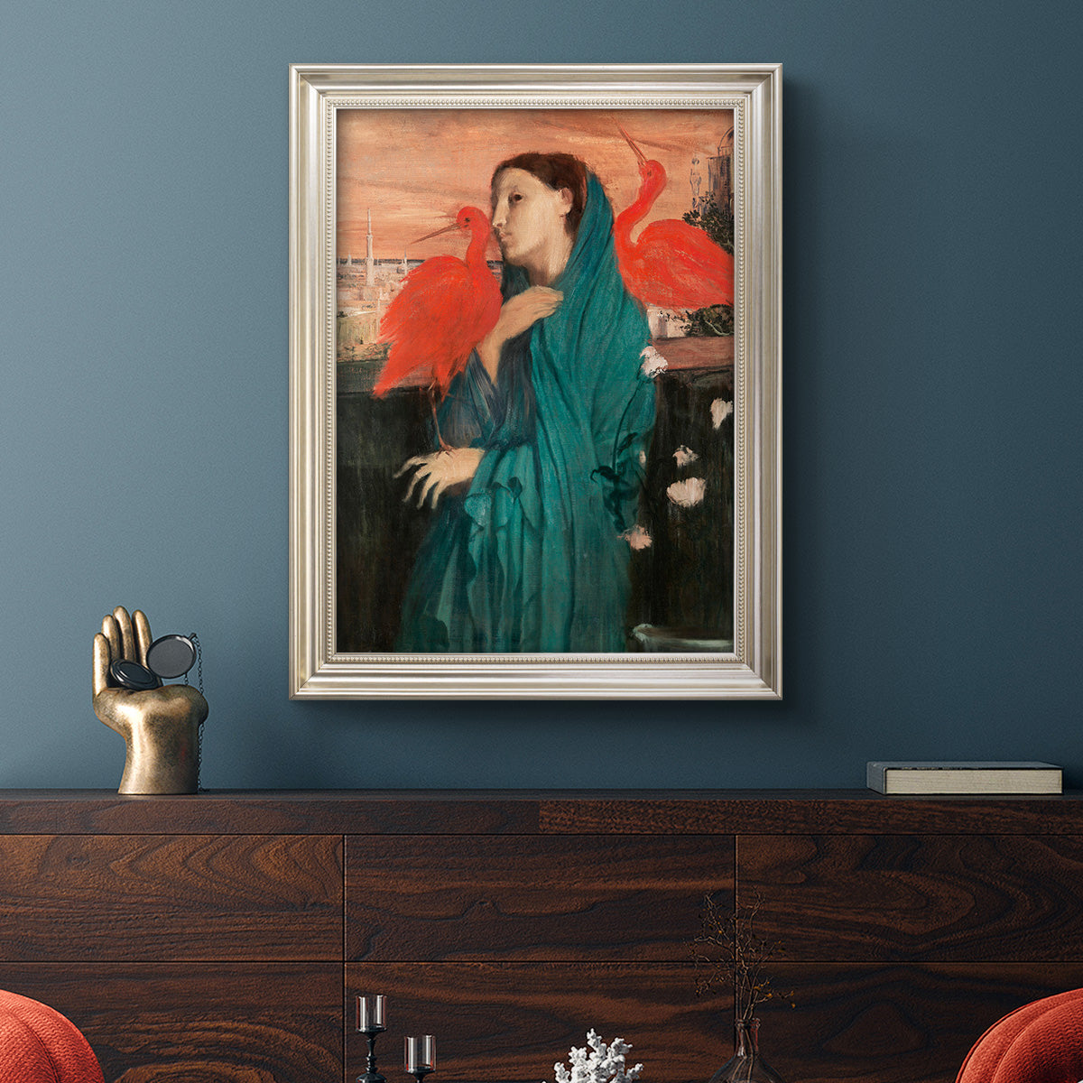Impressionist portrait of a young woman with an ibis by Edgar Degas in an ornate champagne frame displayed in a dark-toned interior setting.