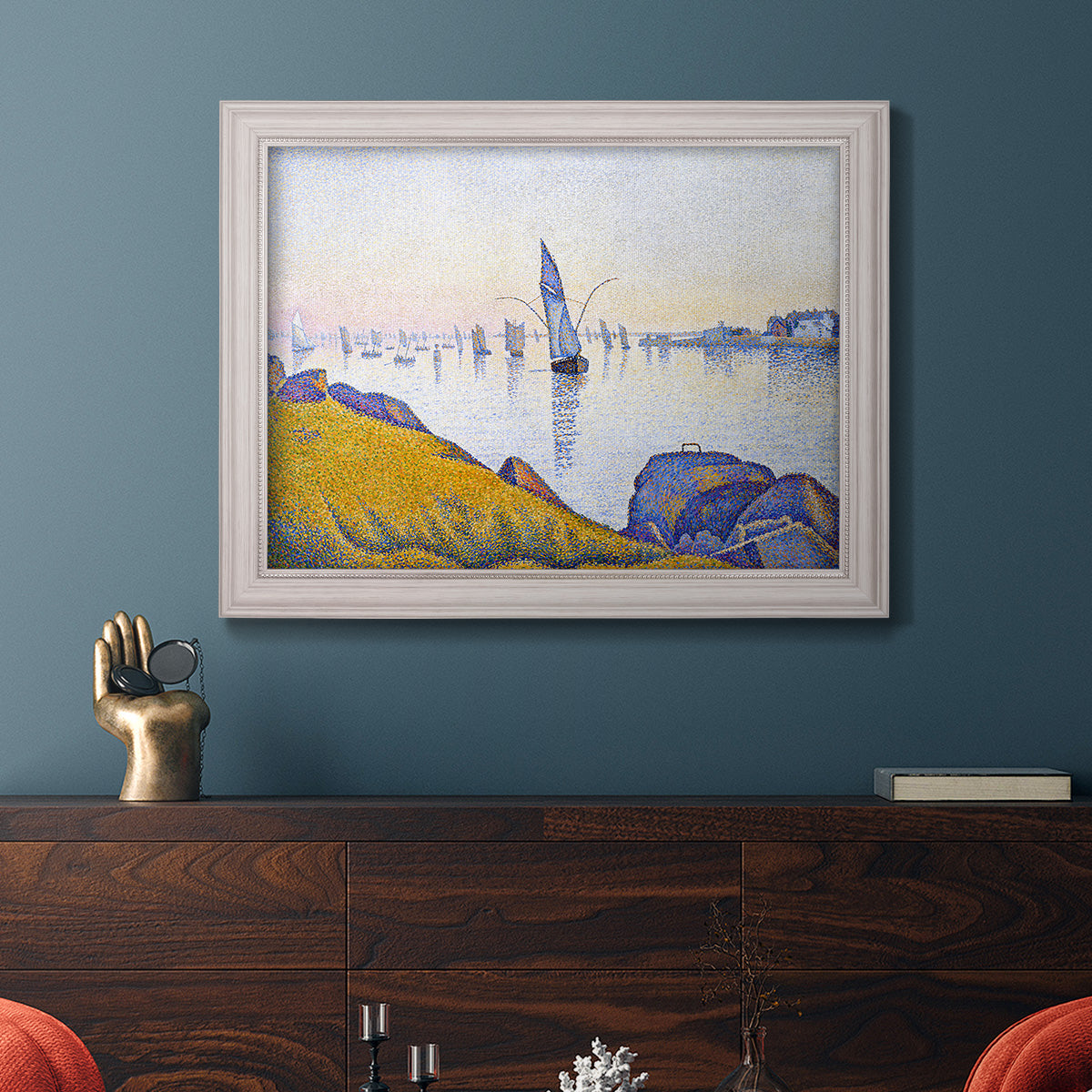 Impressionist coastal harbor at dusk by Paul Signac in an ornate weathered white frame displayed in a dark-toned interior setting.