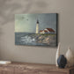 Lighthouse stands tall against crashing waves at a coastal location with birds flying overhead during a calm day