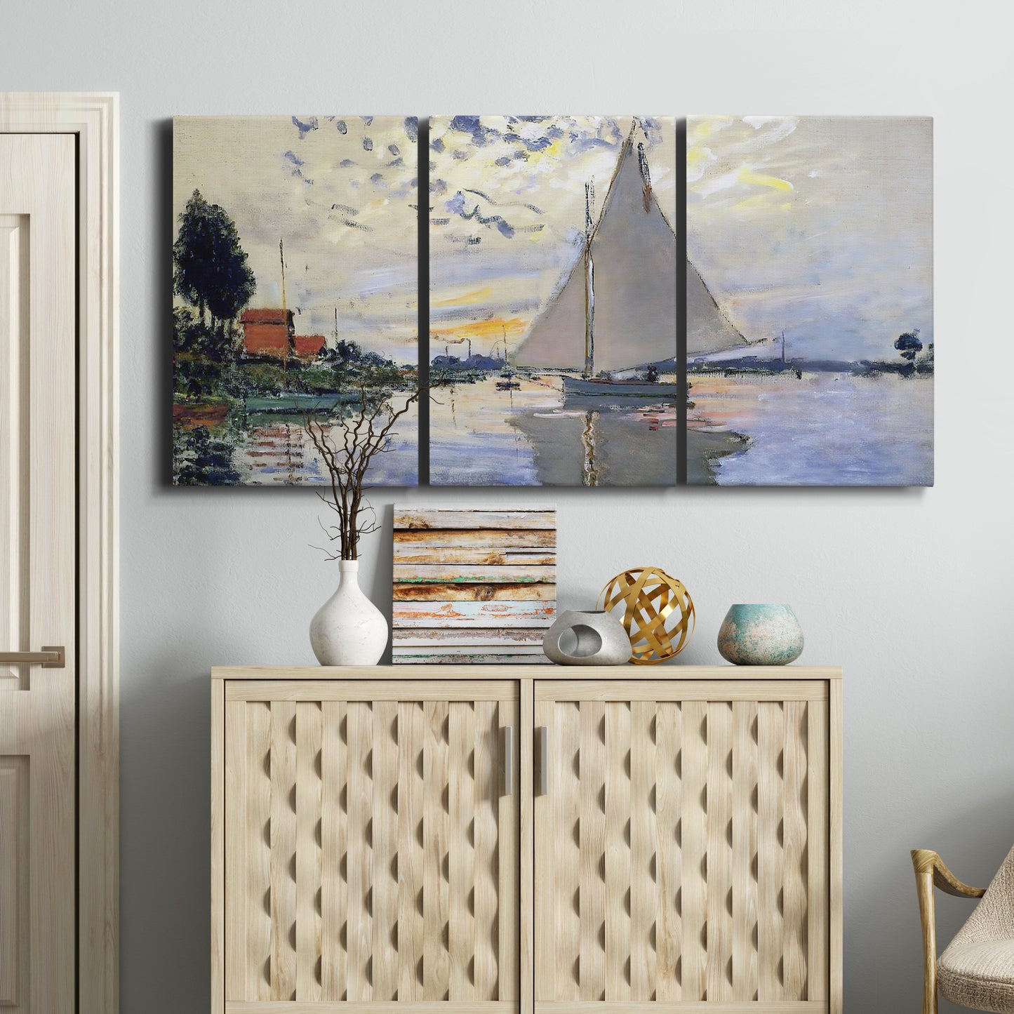 Three-panel canvas wall art featuring riverside village shoreline, displayed above a cabinet in an entryway.