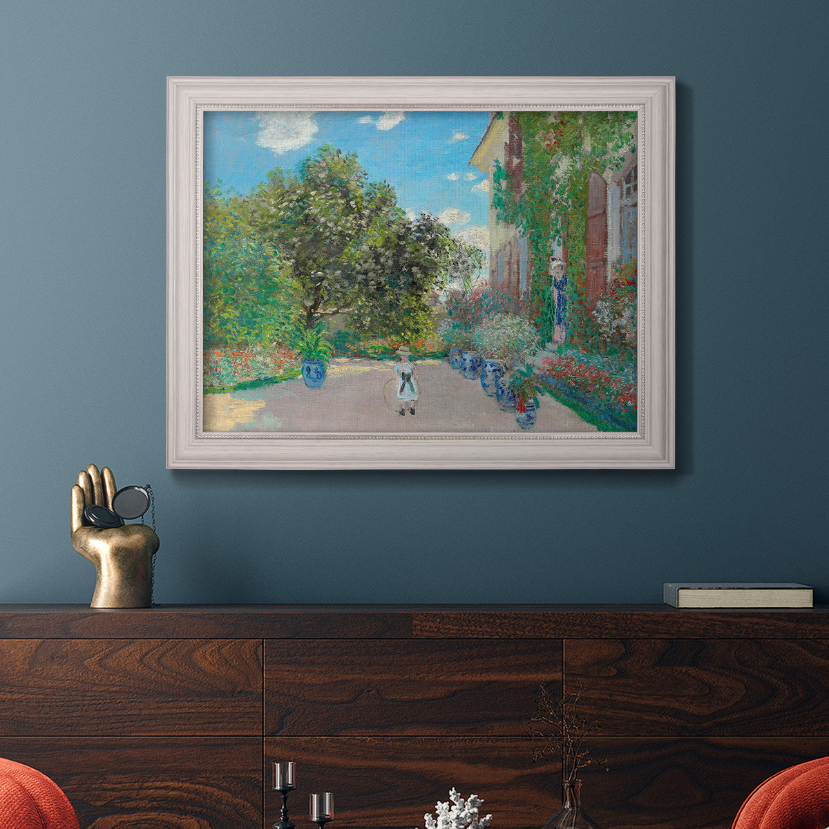Impressionist residential landscape at Argenteuil by Claude Monet in an ornate weathered white frame displayed in a dark-toned interior setting.