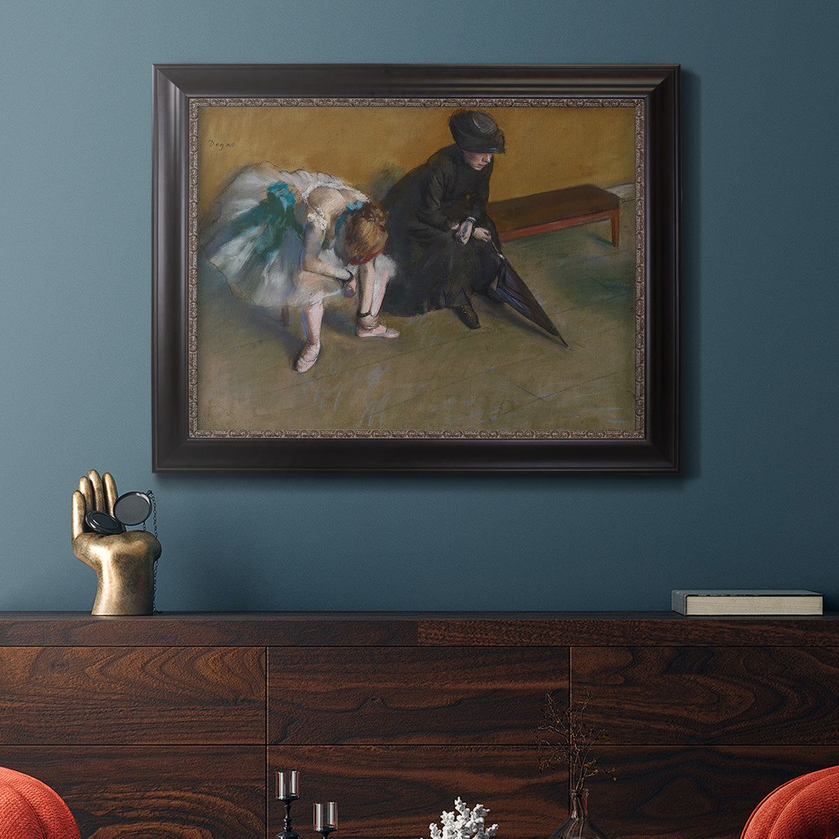 Impressionist portrait of a seated woman by Edgar Degas in an ornate black frame with gilded inner detail displayed in a dark-toned interior setting.