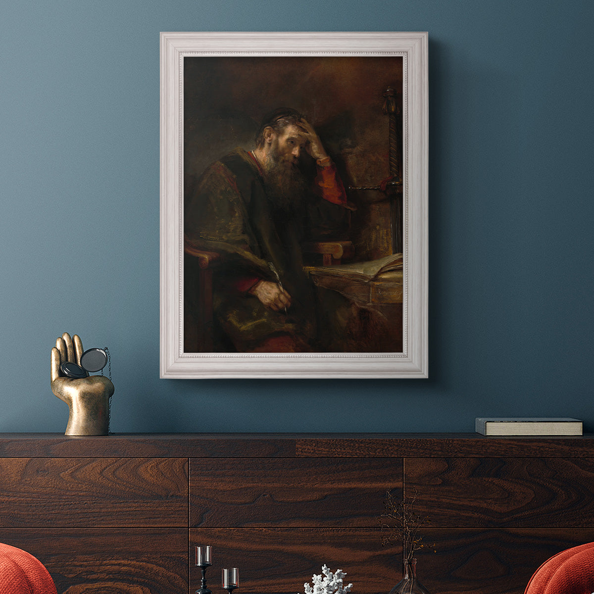 Classical religious portrait of Paul the Apostle by Rembrandt van Rijn in an ornate weathered white frame displayed in a dark-toned interior setting.