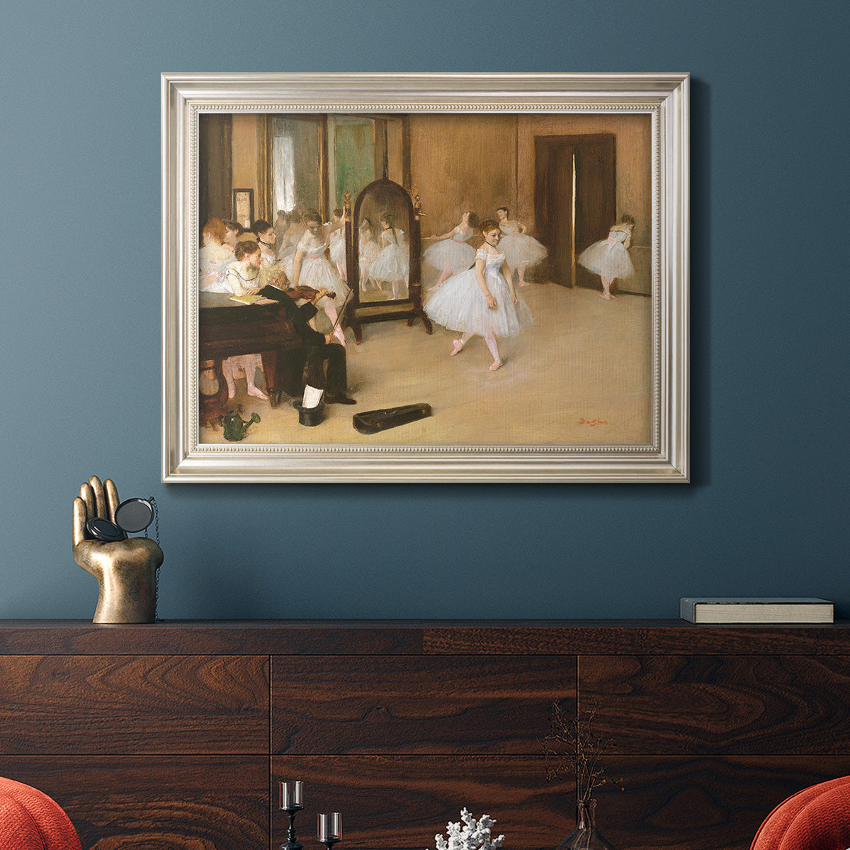 Impressionist dance class interior scene by Edgar Degas in an ornate champagne frame displayed in a dark-toned interior setting.