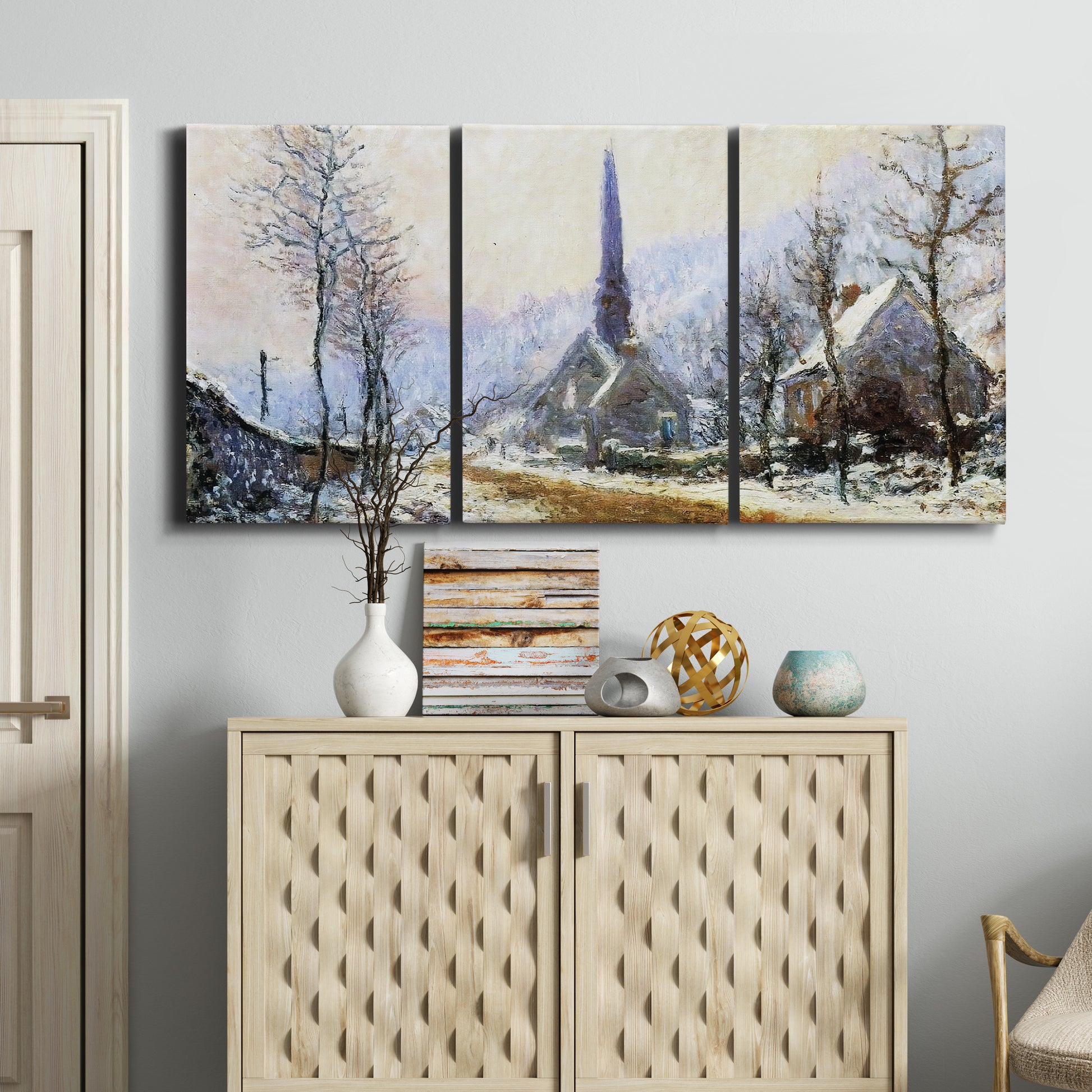 Three-panel canvas wall art featuring snow covered road leading to village, displayed above a cabinet in an entryway.