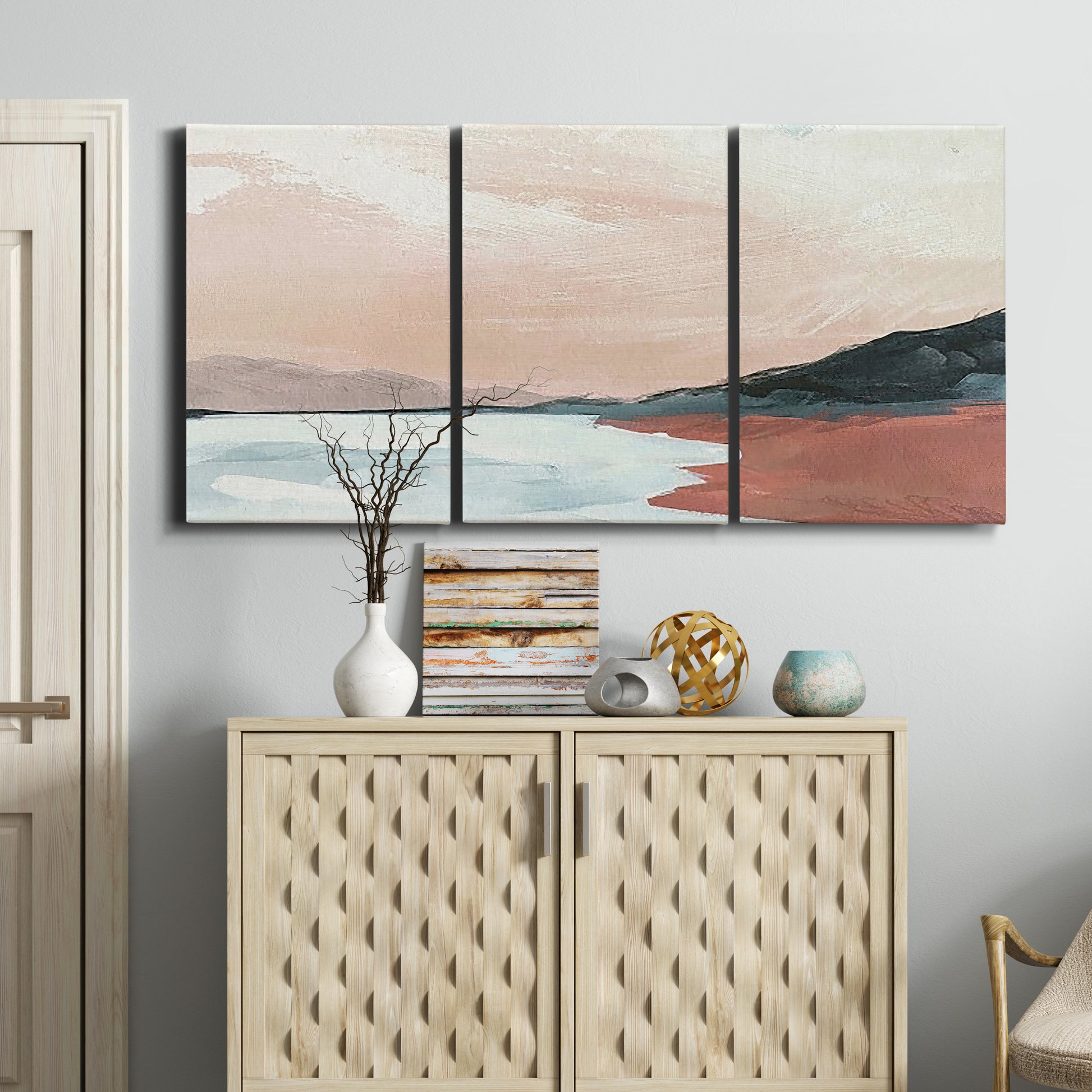 Three-panel canvas wall art featuring quiet coastline with distant horizon, displayed above a cabinet in an entryway.