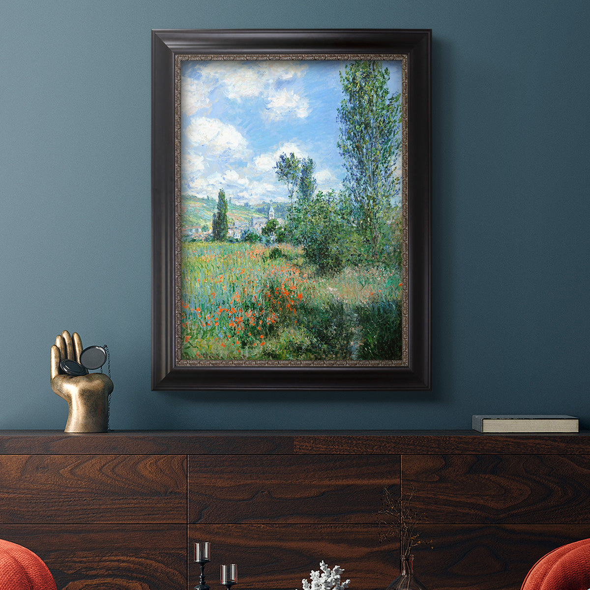 Impressionist pastoral landscape with poppy fields by Claude Monet in an ornate black frame with gilded inner detail displayed in a dark-toned interior setting.
