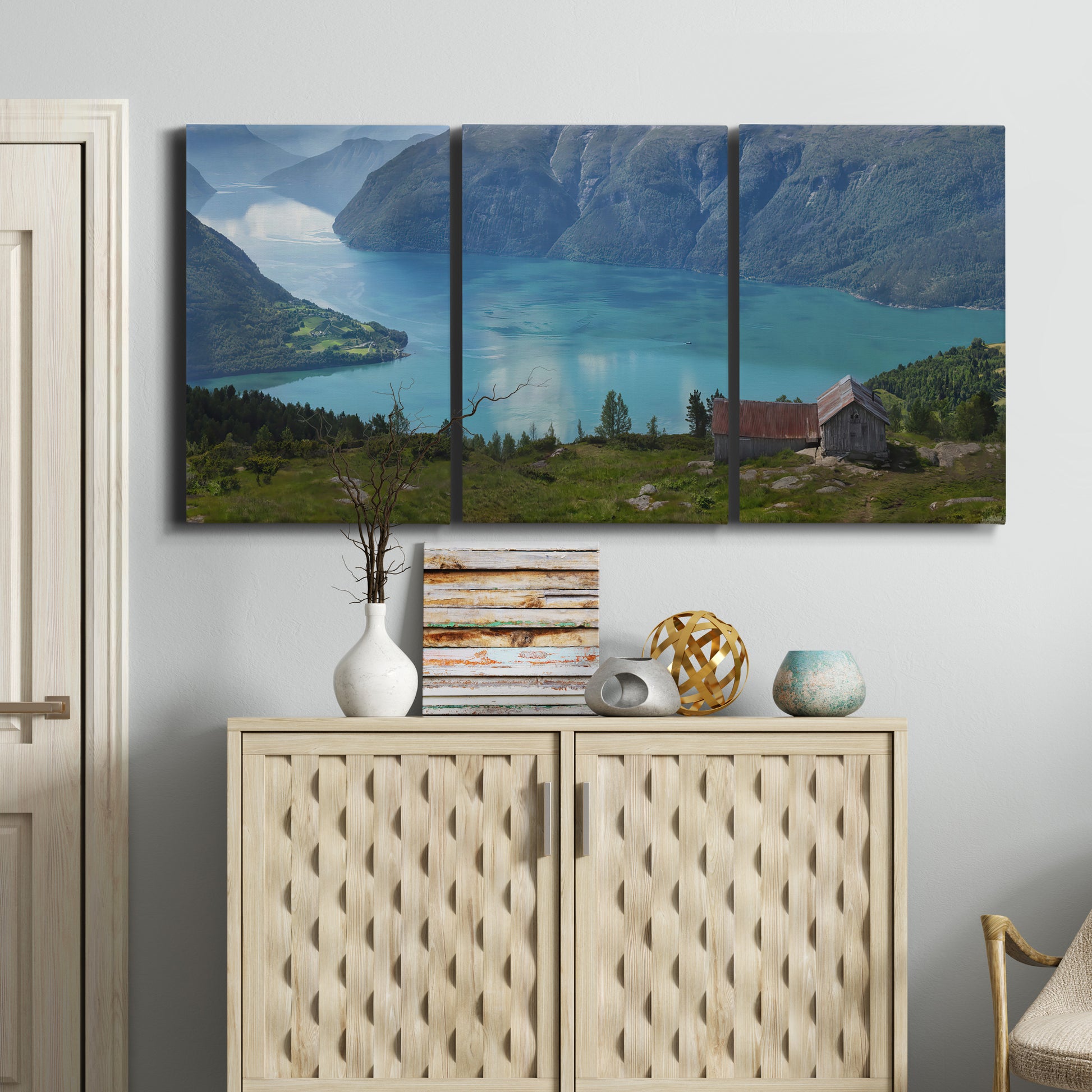 Three-panel canvas wall art featuring symmetrical water reflections with trees, displayed above a cabinet in an entryway.