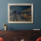 Impressionist nighttime Paris street scene by Camille Pissarro in an ornate champagne frame displayed in a dark-toned interior setting.