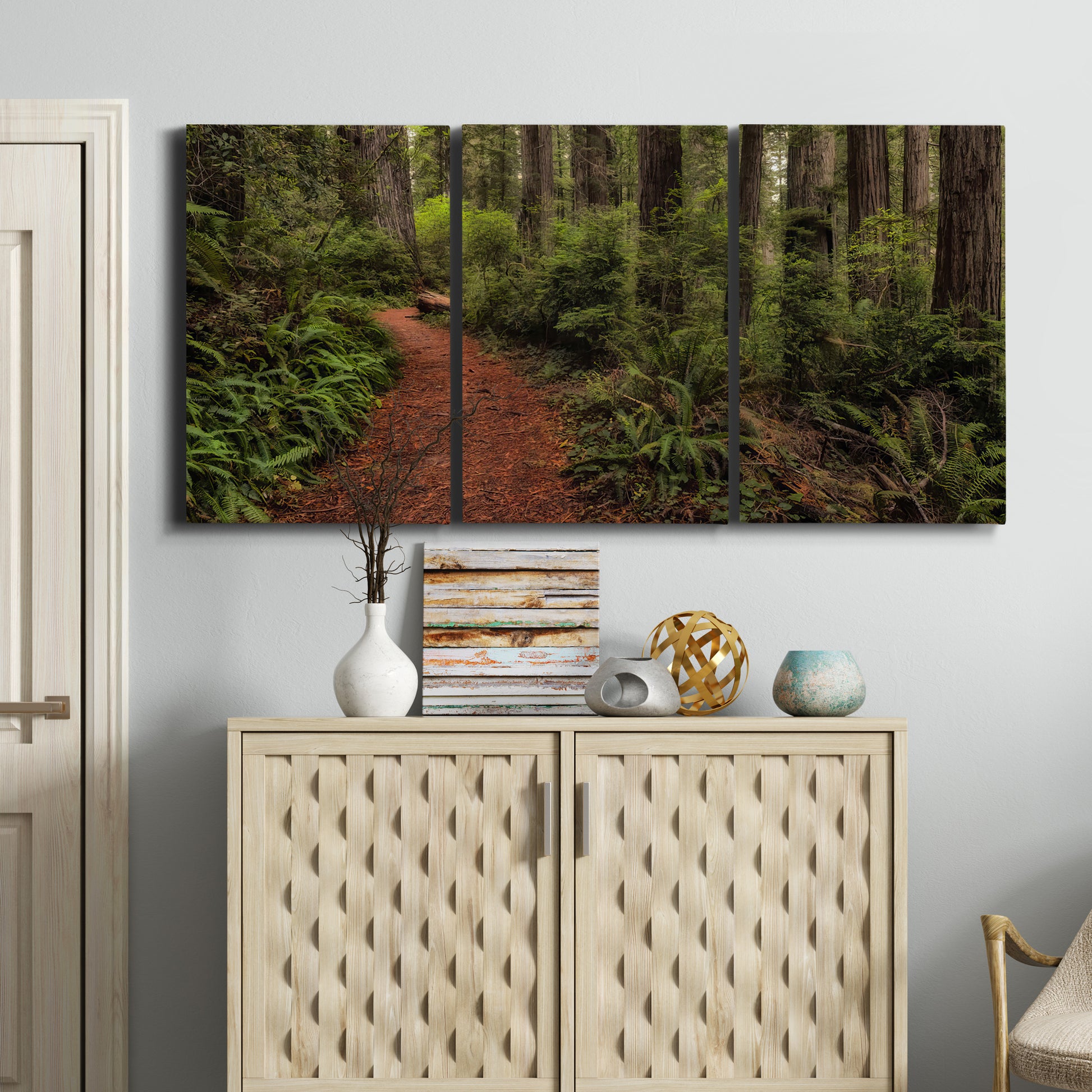 Three-panel canvas wall art featuring forest trail landscape photograph, displayed above a cabinet in an entryway.