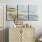 Three-panel canvas wall art featuring coastal cove with calm water, displayed above a cabinet in an entryway.