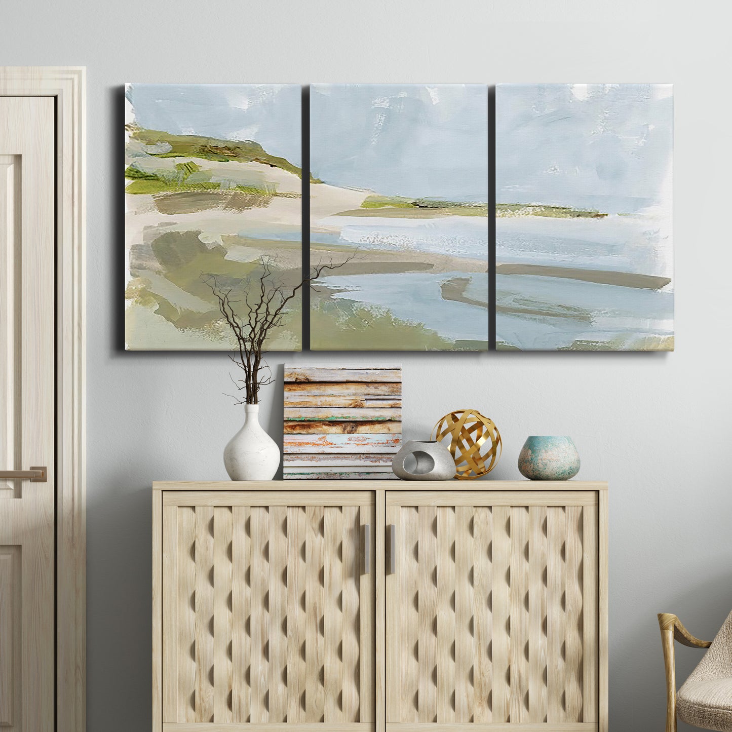 Three-panel canvas wall art featuring coastal cove with calm water, displayed above a cabinet in an entryway.
