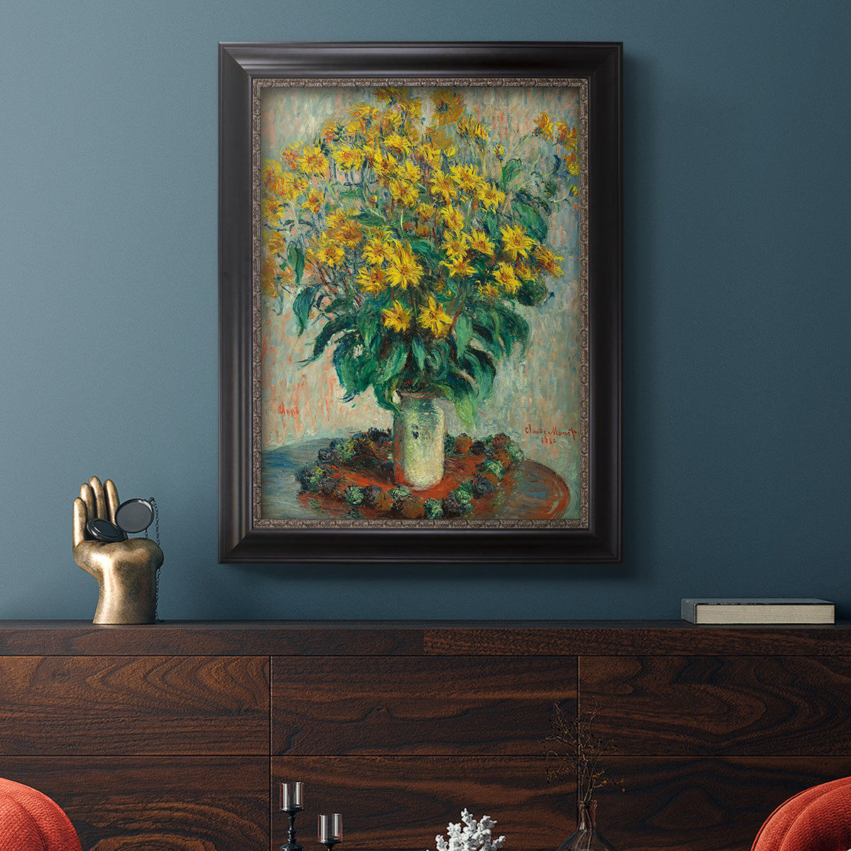 Impressionist floral painting of artichoke flowers by Claude Monet in an ornate black frame with gilded inner detail displayed in a dark-toned interior setting.