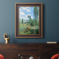 Impressionist pastoral landscape with poppy fields by Claude Monet in an ornate bronzed mahogany wood frame displayed in a dark-toned interior setting.