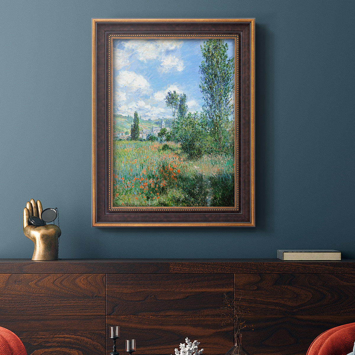 Impressionist pastoral landscape with poppy fields by Claude Monet in an ornate bronzed mahogany wood frame displayed in a dark-toned interior setting.