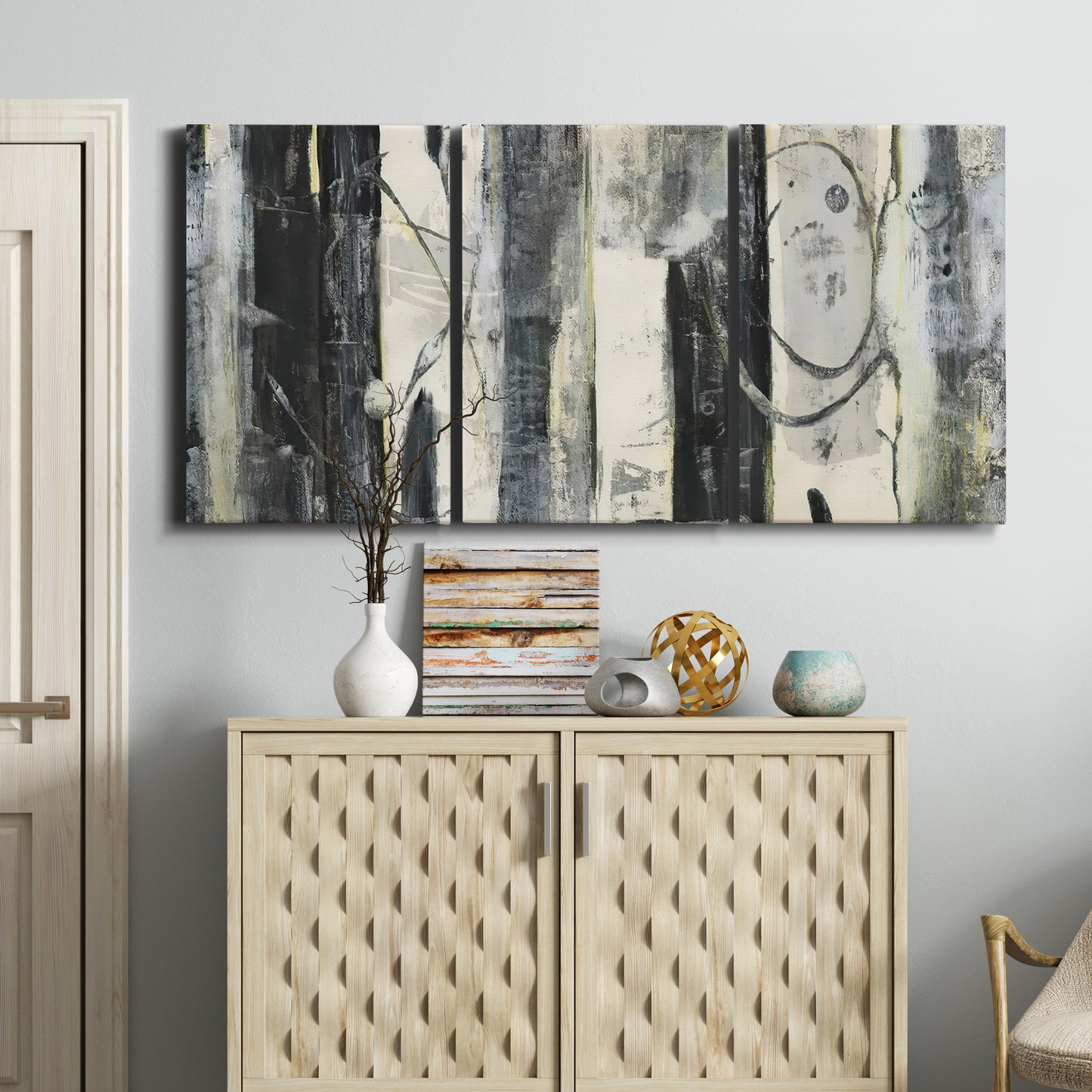 Three-panel canvas wall art featuring vertical abstract tree forms, displayed above a cabinet in an entryway.
