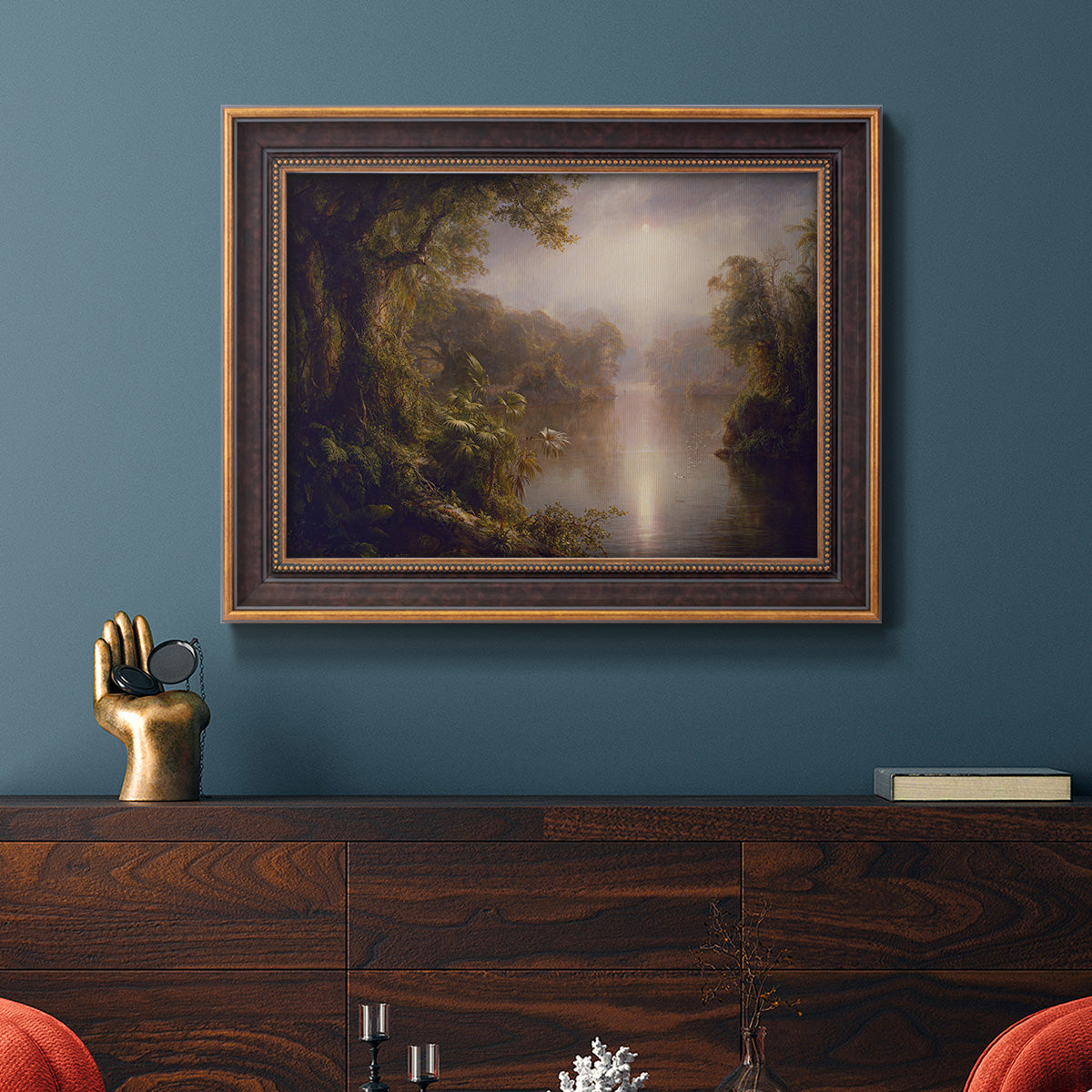 Luminous romantic landscape painting by Frederic Edwin Church in an ornate bronzed mahogany wood frame displayed in a dark-toned interior setting.