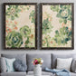 Set of two black barnwood framed canvas prints depicting paired decorative botanical pattern prints with green rosettes, peach blossoms, and mosaic-like outlines above a sofa in a contemporary living room.