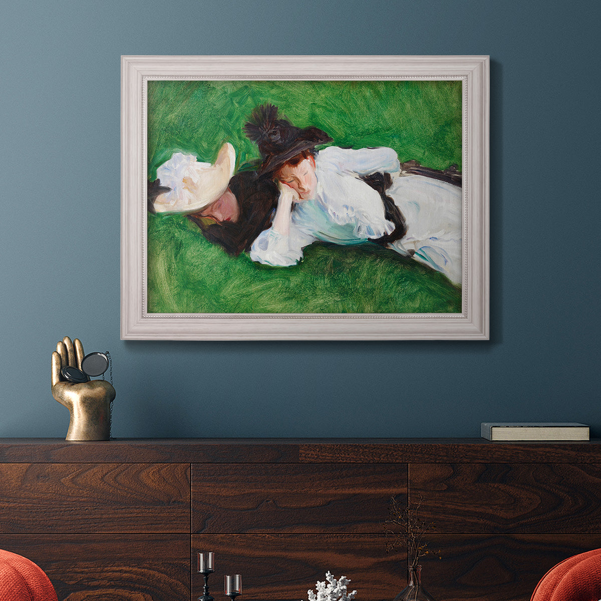 Impressionist outdoor portrait of two girls by John Singer Sargent in an ornate weathered white frame displayed in a dark-toned interior setting.