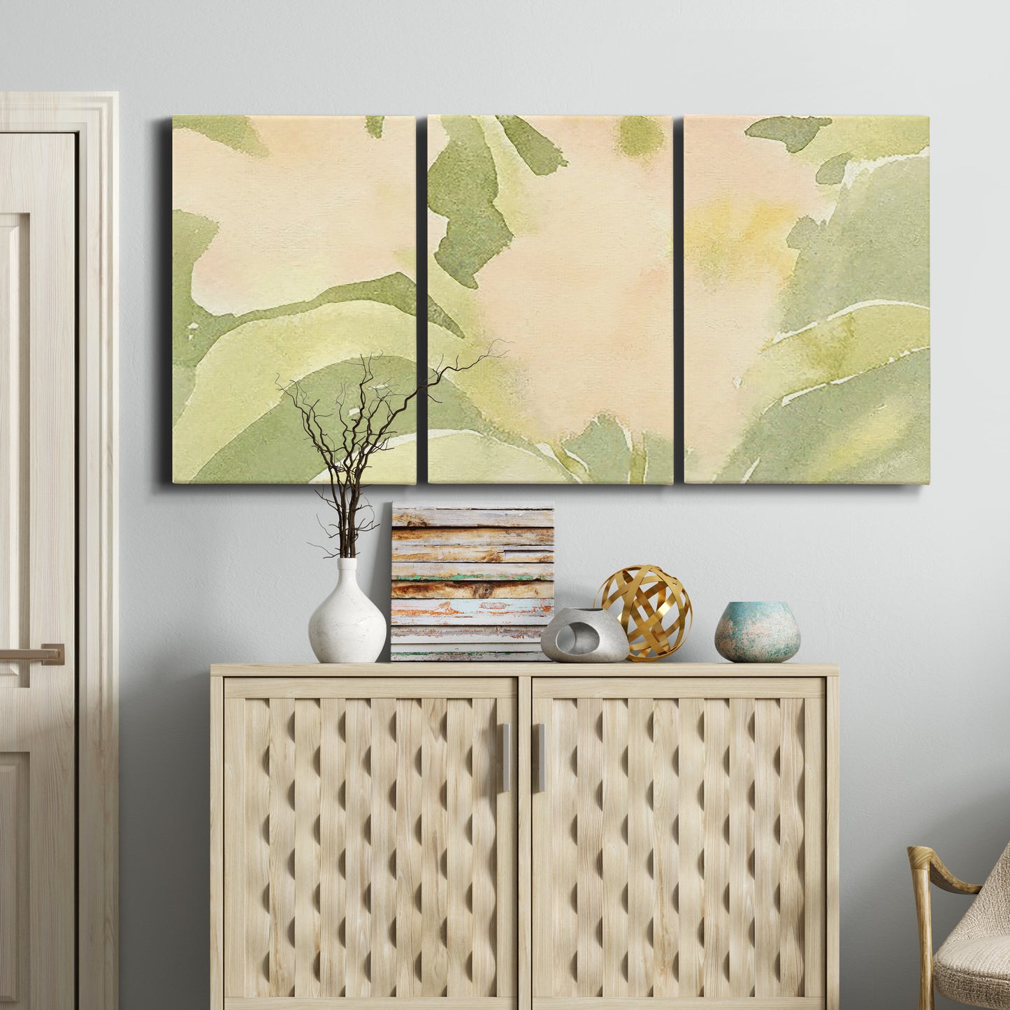 Three-panel canvas wall art featuring minimal verdant floral abstraction, displayed above a cabinet in an entryway.