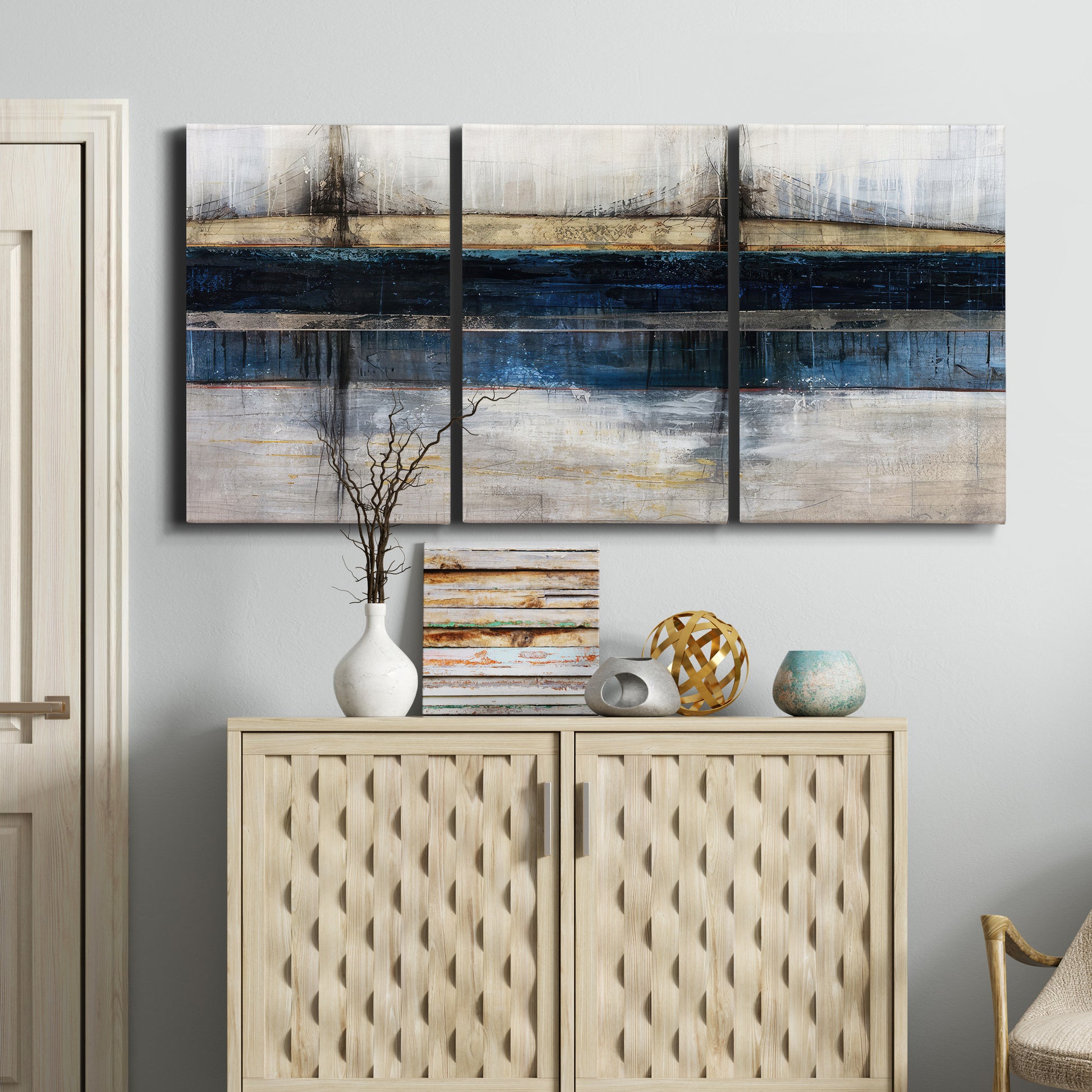 Three-panel canvas wall art featuring abstract blue urban composition, displayed above a cabinet in an entryway.