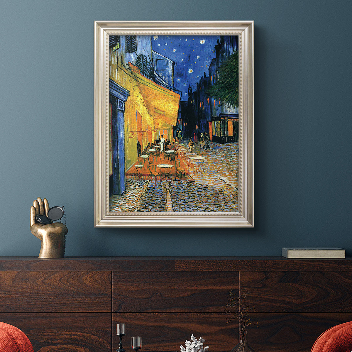 Impressionist night café street scene by Vincent van Gogh in an ornate champagne frame displayed in a dark-toned interior setting.