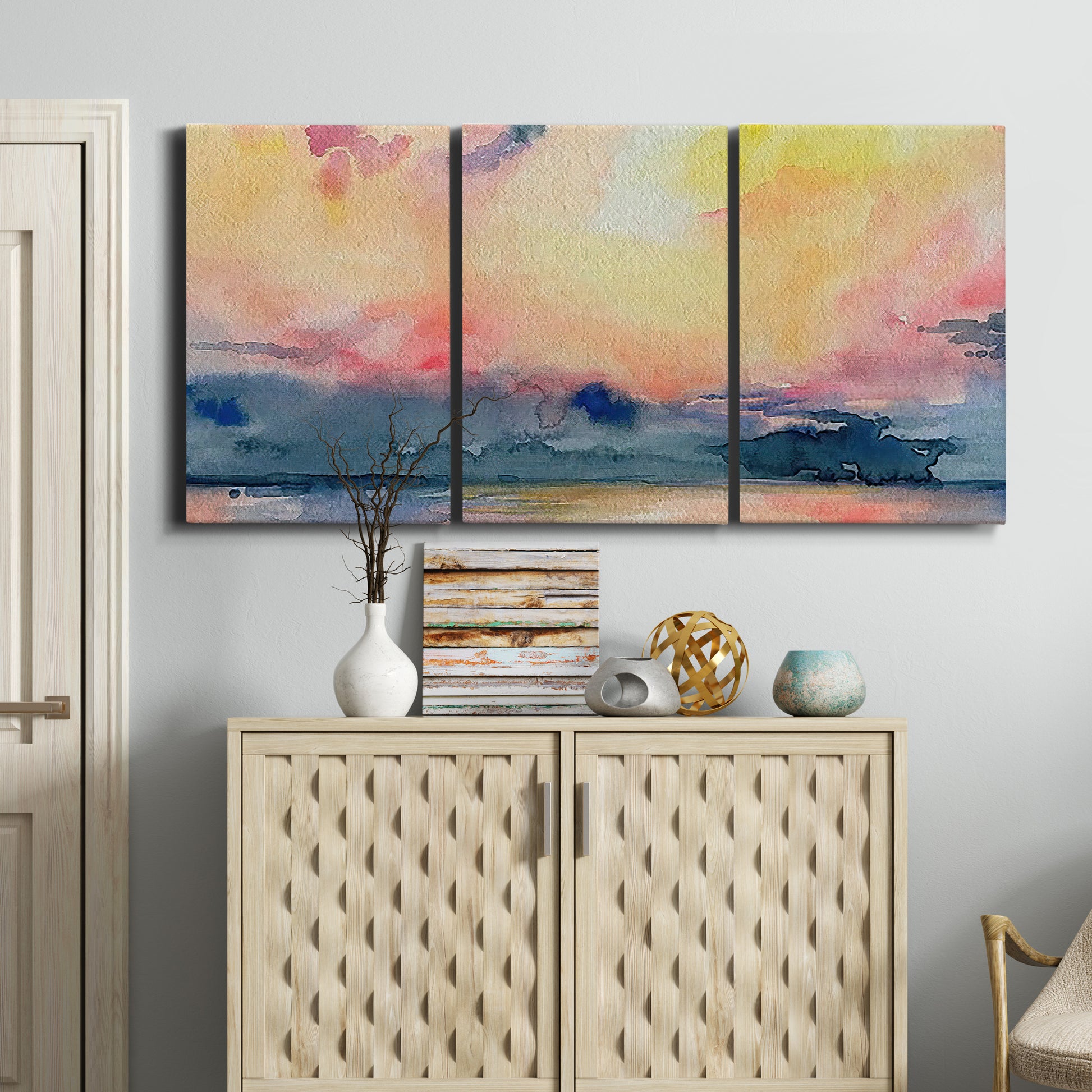 Three-panel canvas wall art featuring prismatic watercolor coastal seascape, displayed above a cabinet in an entryway.