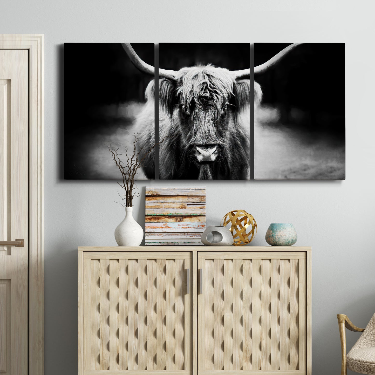 Three-panel canvas wall art featuring black and white cattle portrait, displayed above a cabinet in an entryway.