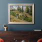 Impressionist countryside harvest scene by Camille Pissarro in an ornate champagne frame displayed in a dark-toned interior setting.