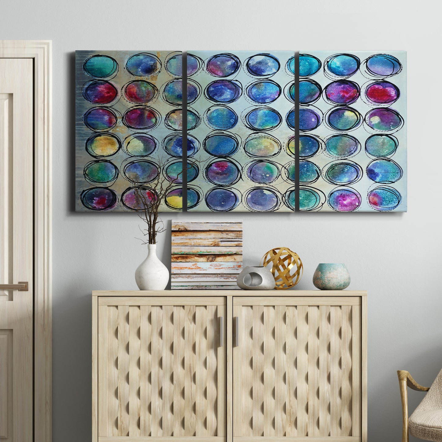 Three-panel canvas wall art featuring contrasting geometric abstract variations, displayed above a cabinet in an entryway.