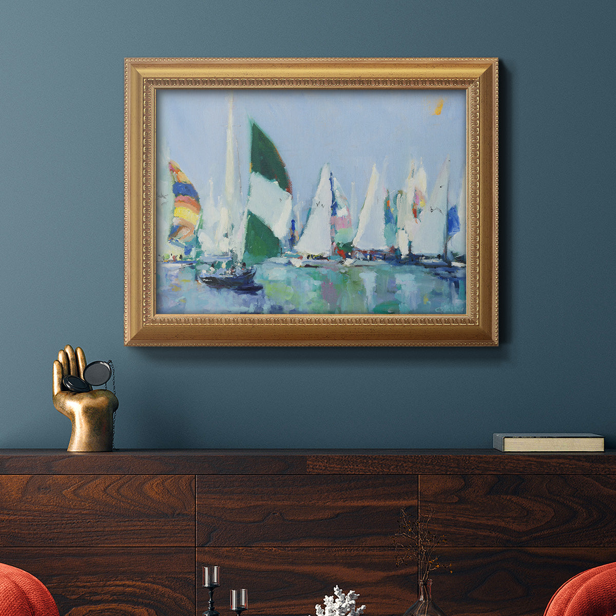 Coastal harbor watercolor painting in an ornate antique gold frame displayed in a dark-toned interior setting.