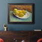 Impressionist still life with lemons by Vincent van Gogh in an ornate black frame with gilded inner detail displayed in a dark-toned interior setting.
