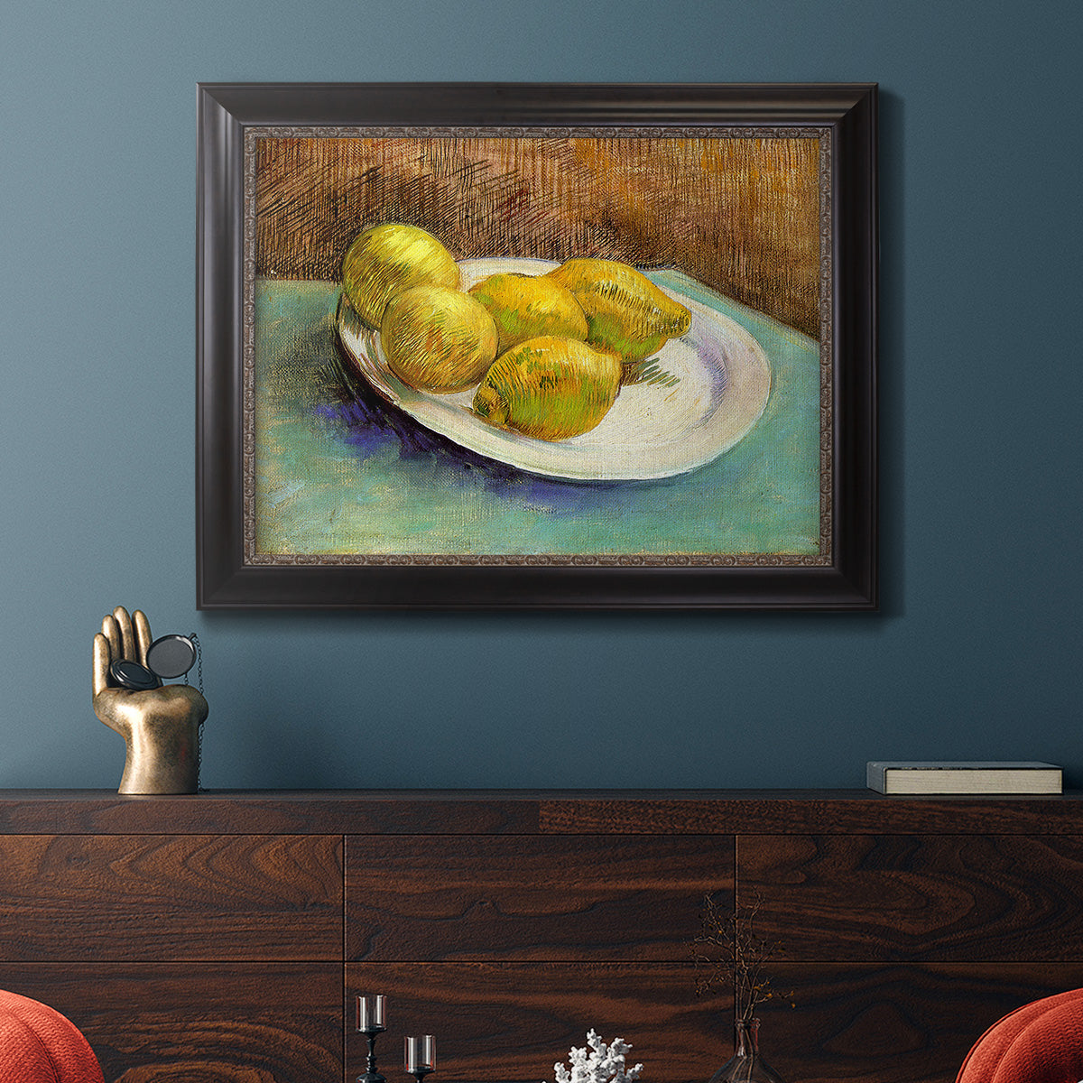 Impressionist still life with lemons by Vincent van Gogh in an ornate black frame with gilded inner detail displayed in a dark-toned interior setting.