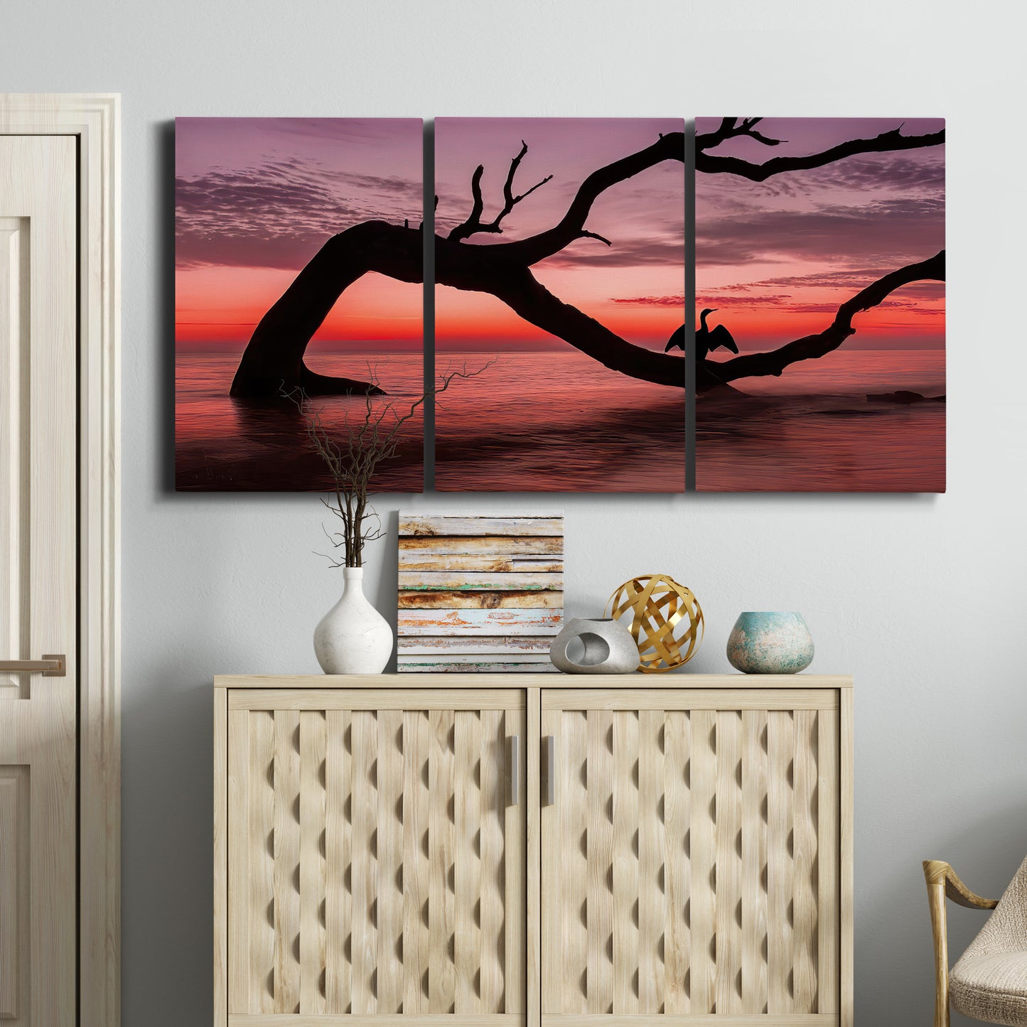Three-panel canvas wall art featuring sunset beach photography, displayed above a cabinet in an entryway.