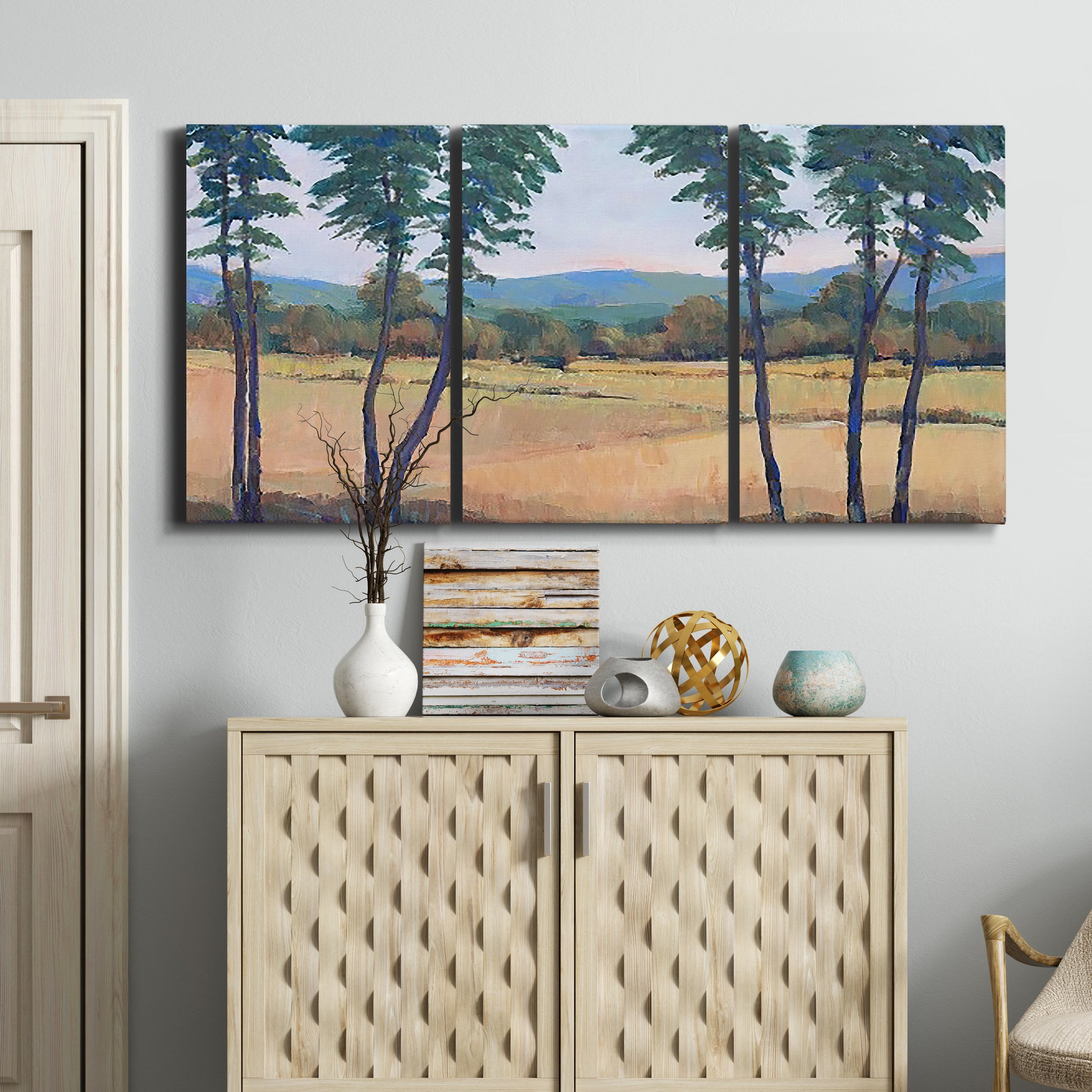 Three-panel canvas wall art featuring quiet morning landscape with trees, displayed above a cabinet in an entryway.