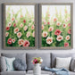 Set of two gray barnwood framed canvas prints depicting paired luminous impressionistic floral paintings with loose blossoms, green stems, and sunlit watercolor texture above a sofa in a contemporary living room.