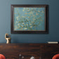 Impressionist flowering almond branch painting by Vincent van Gogh in an ornate black frame with gilded inner detail displayed in a dark-toned interior setting.