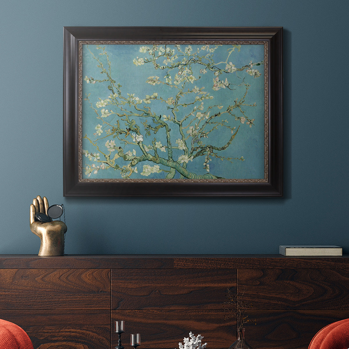 Impressionist flowering almond branch painting by Vincent van Gogh in an ornate black frame with gilded inner detail displayed in a dark-toned interior setting.