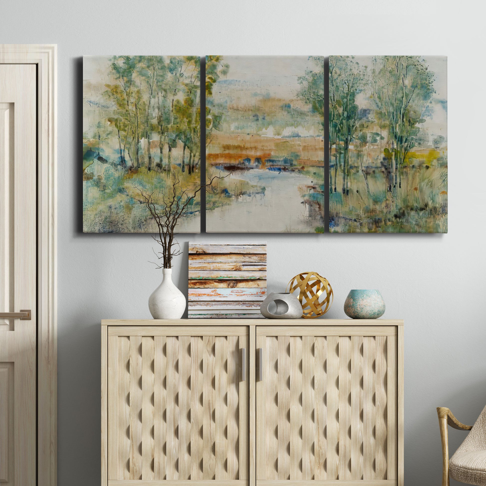 Three-panel canvas wall art featuring trees lining quiet creek, displayed above a cabinet in an entryway.