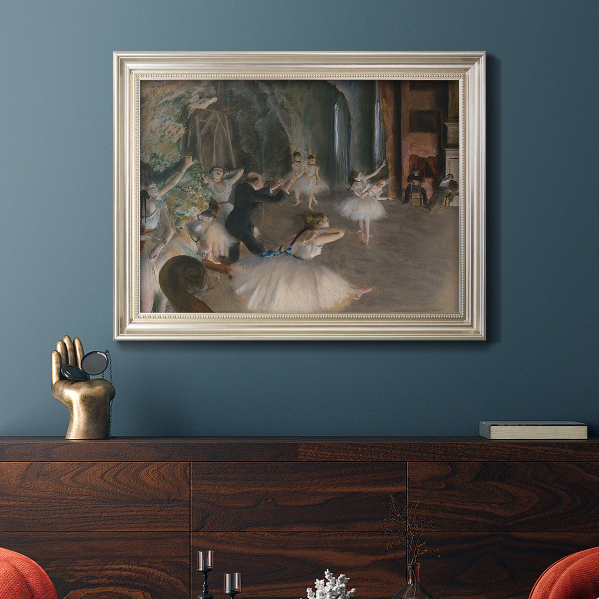 Impressionist backstage ballet scene by Edgar Degas in an ornate champagne frame displayed in a dark-toned interior setting.