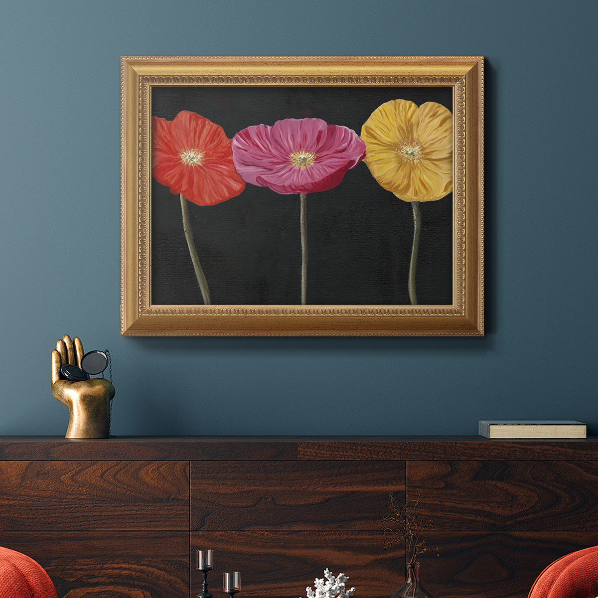 Contemporary poppy flower artwork in an ornate antique gold frame displayed in a dark-toned interior setting.