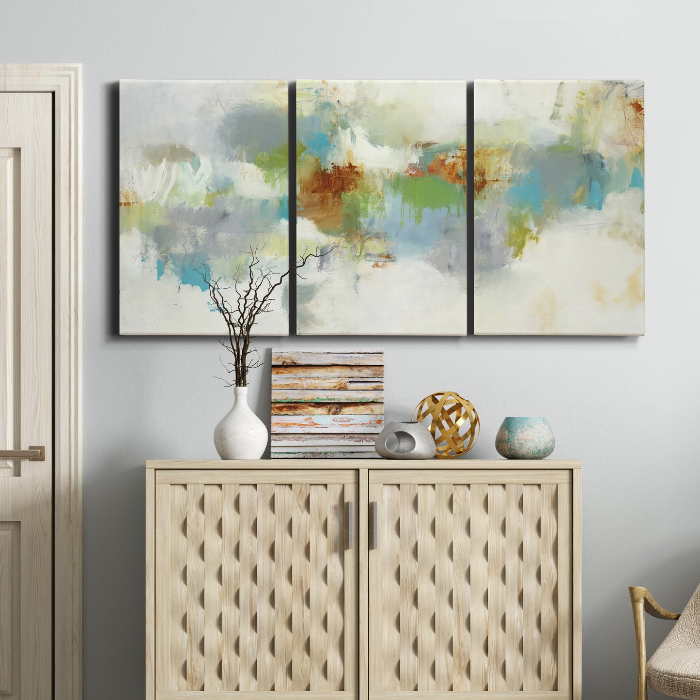 Three-panel canvas wall art featuring abstract suggestion of discovery, displayed above a cabinet in an entryway.